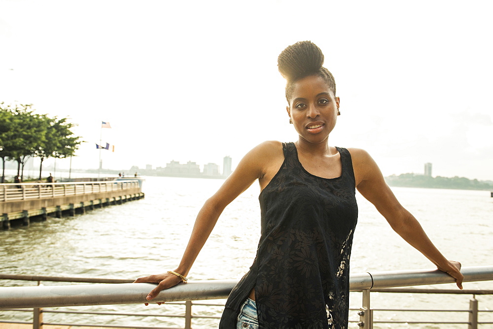 Portrait of African American woman leaning on railing at waterfront