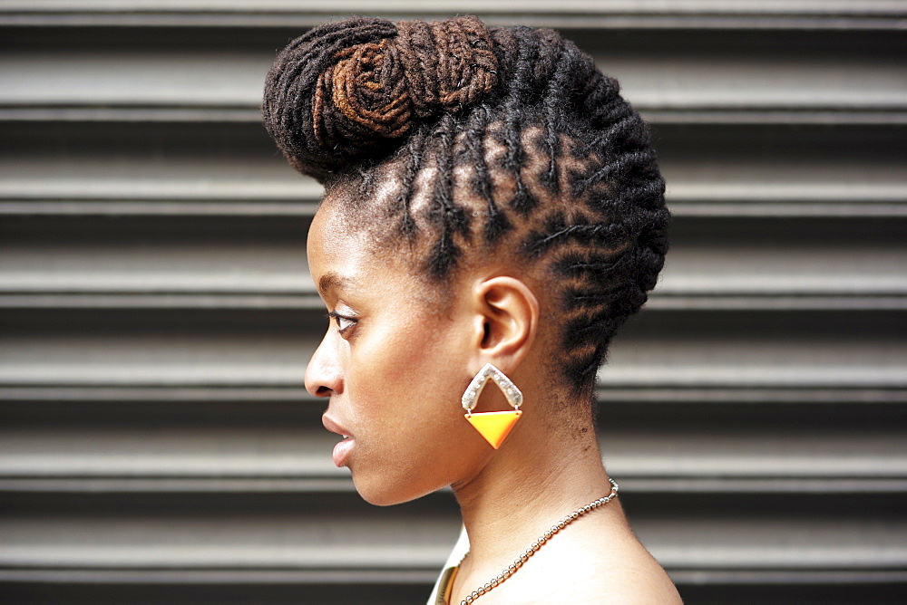 Profile of African American woman with braids near metal wall