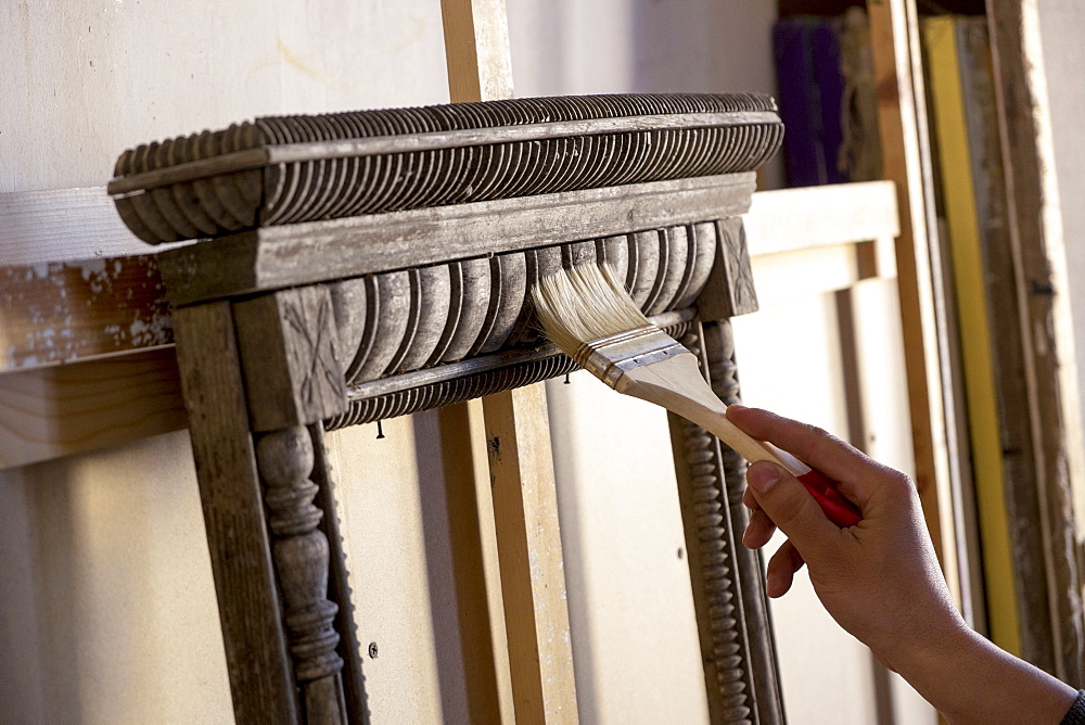 Hand of Caucasian man using paintbrush on picture frame