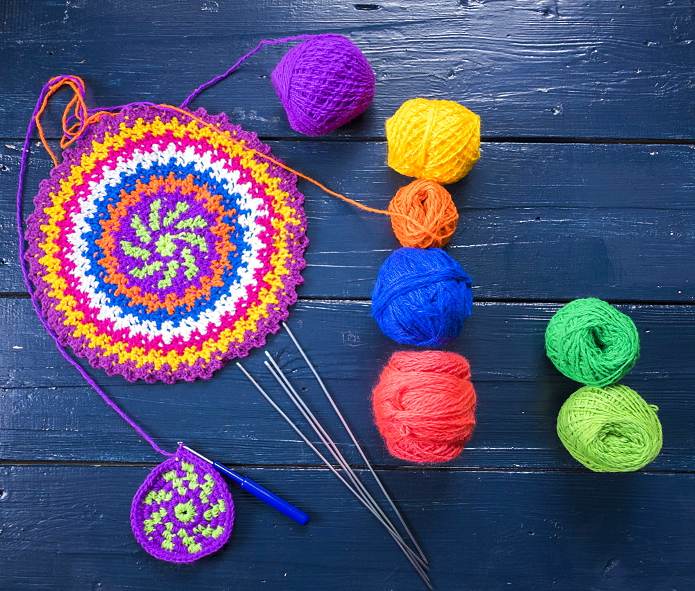 Knitting needles and multicolor yarn on blue table