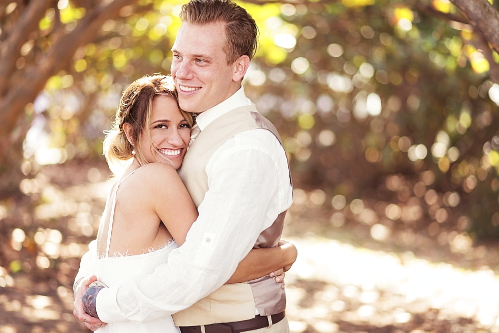 Caucasian bride and groom hugging outdoors