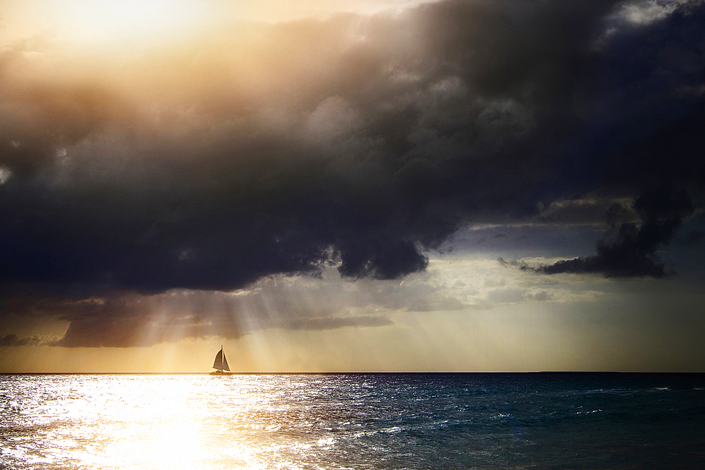 Sunbeams through storm clouds over sailboat