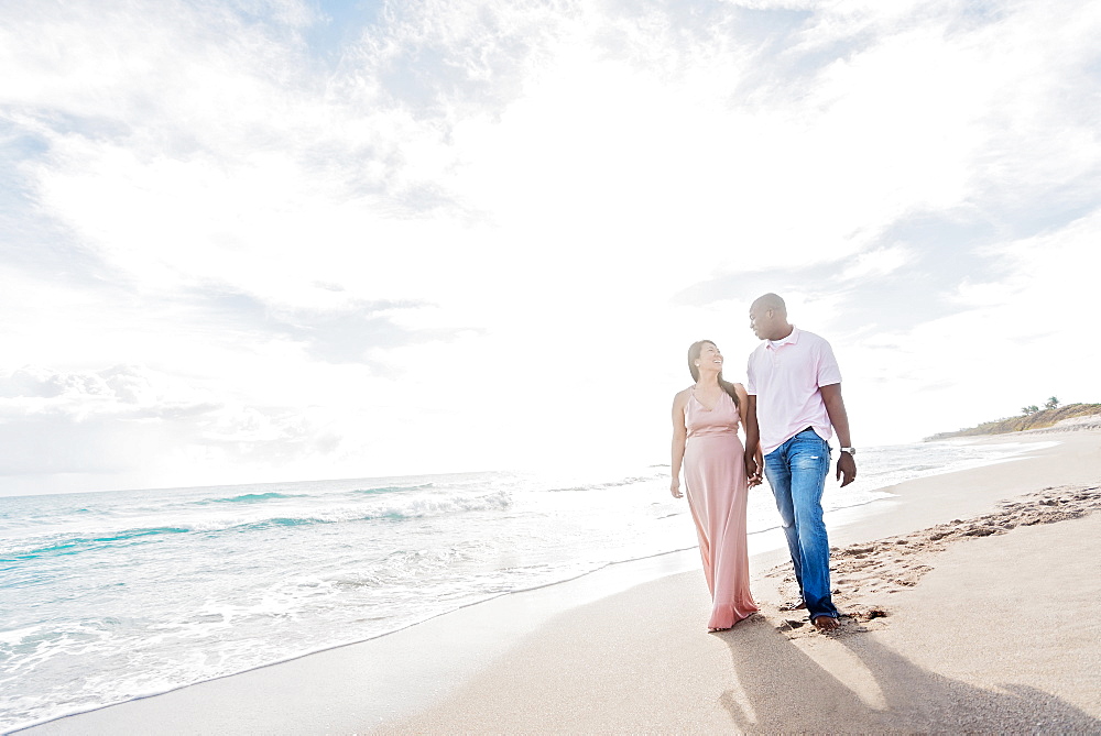 Couple holding hands walking on beach