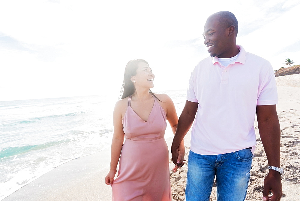 Couple holding hands walking on beach