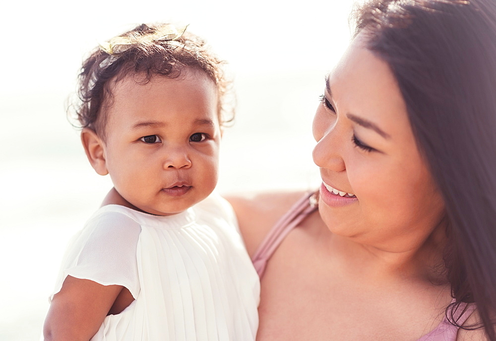 Portrait of mother holding baby daughter near ocean