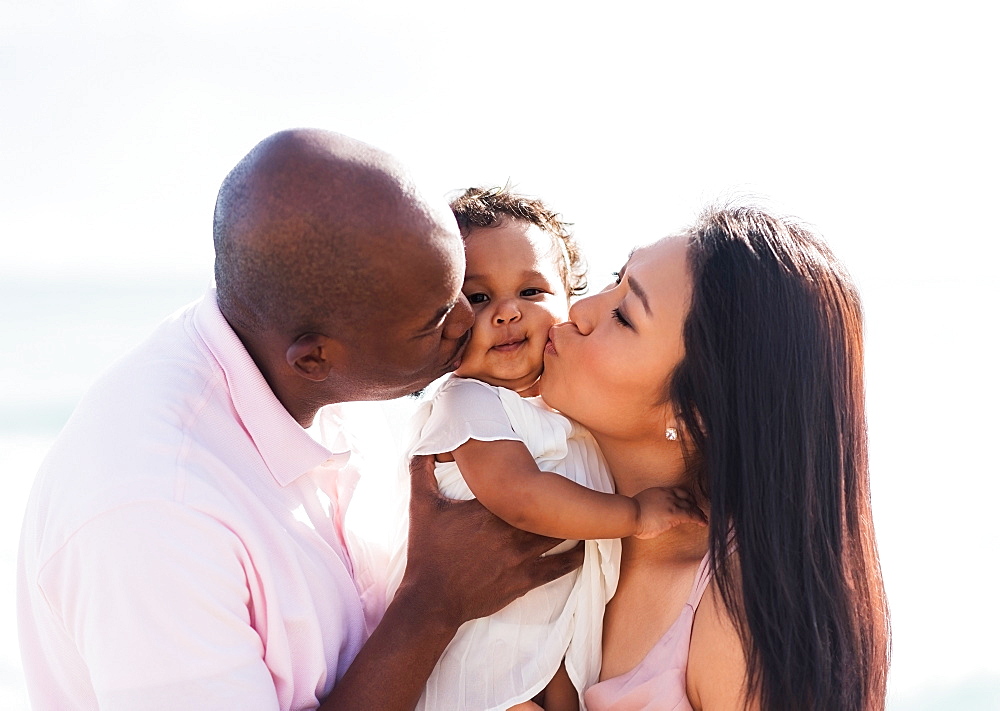 Couple kissing cheeks of baby daughter