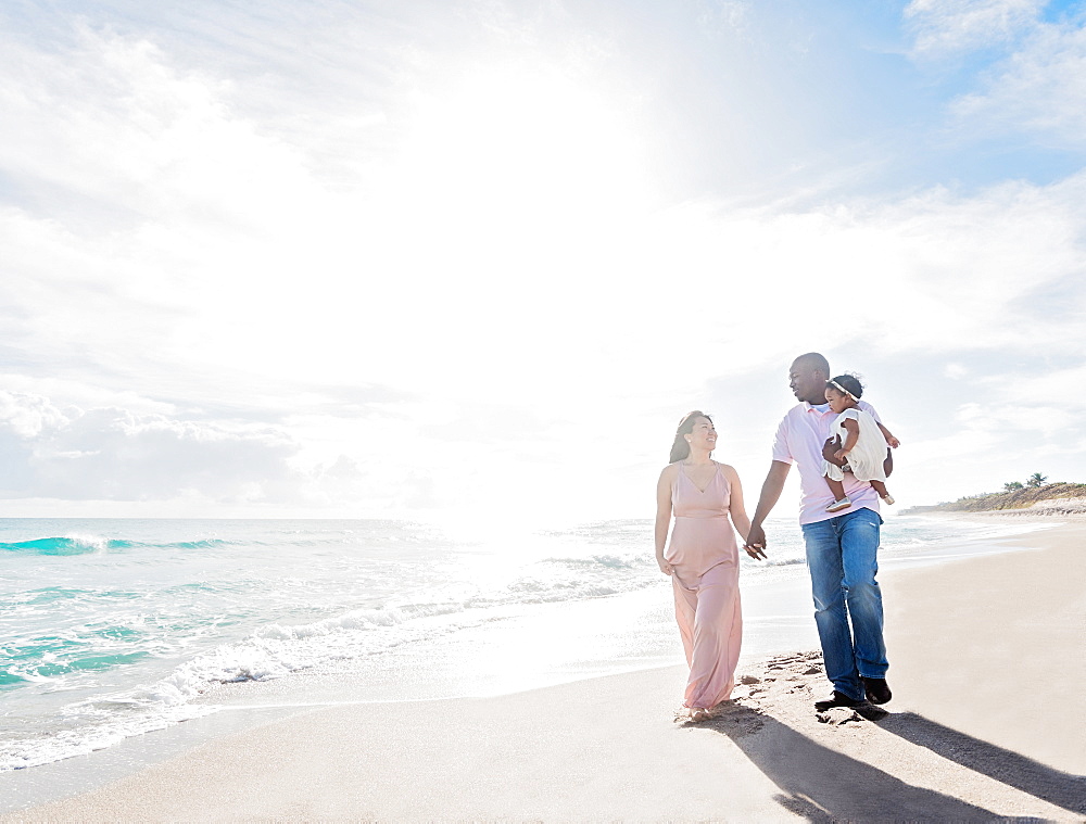 Couple walking on beach with baby daughter