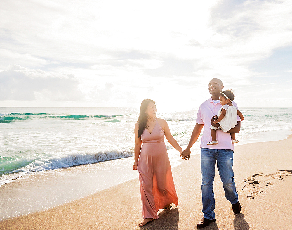 Couple walking on beach with baby daughter