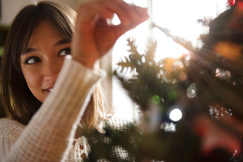 Mixed Race woman placing tinsel on Christmas tree