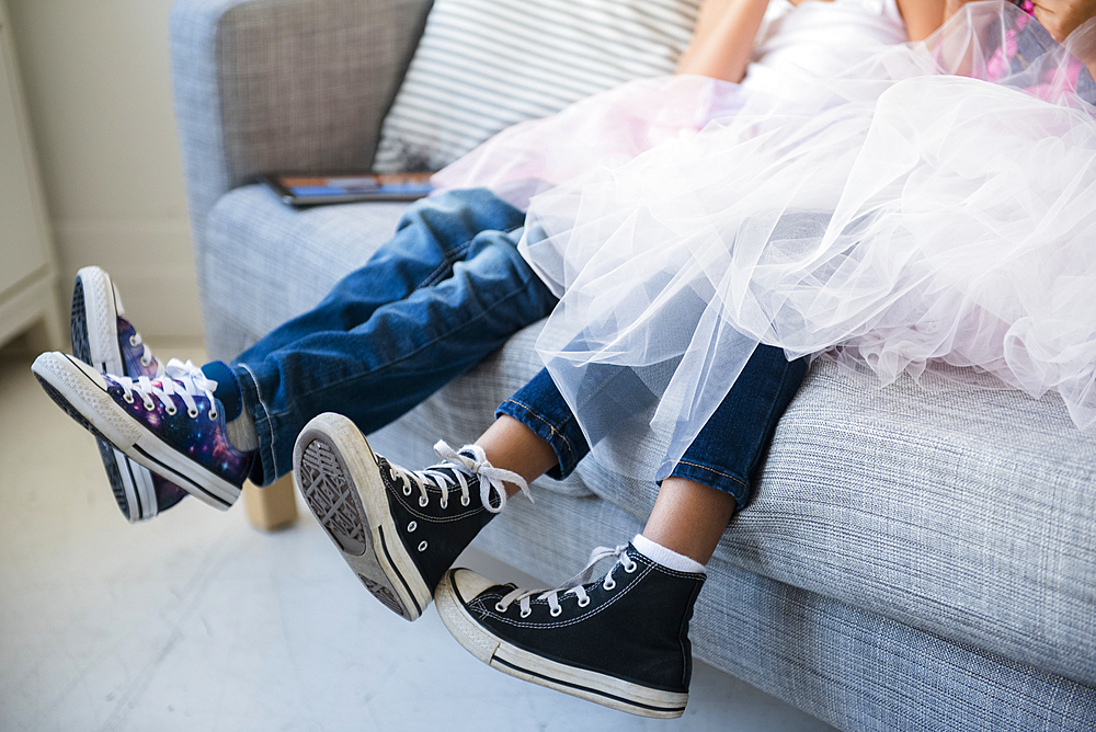 Legs of girls wearing tutus on sofa