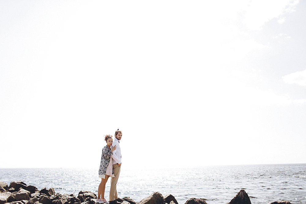 Middle Eastern couple standing on rocks near ocean