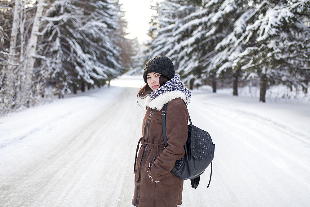 Asian woman carrying backpack on snowy road