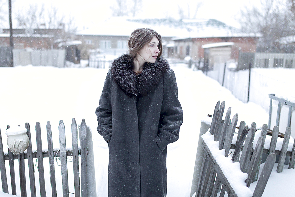 Caucasian woman wearing coat in winter near fence