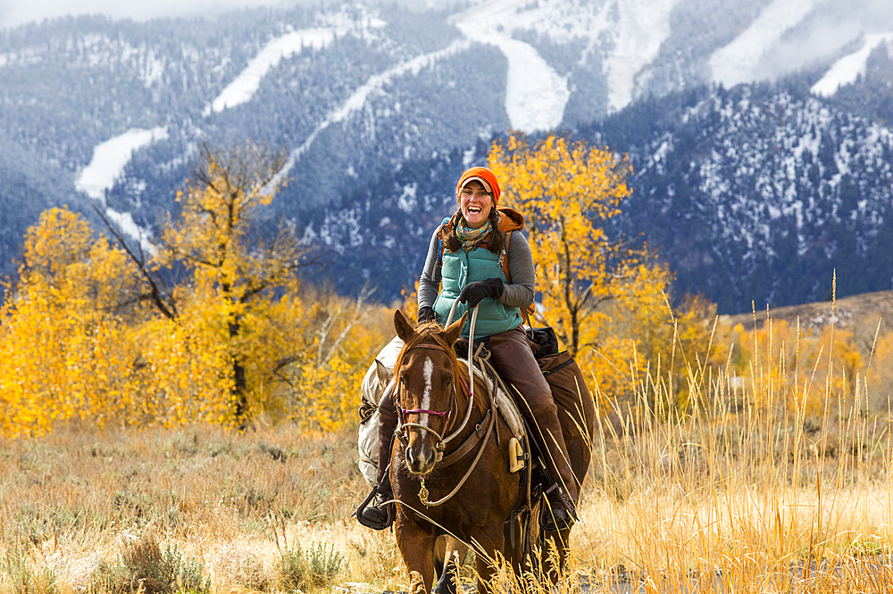 Laughing Caucasian woman riding horse in winter