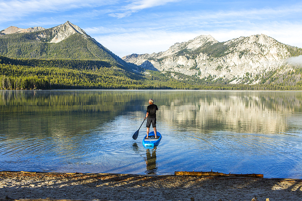 Caucasian man paddleboarding on mountain lake