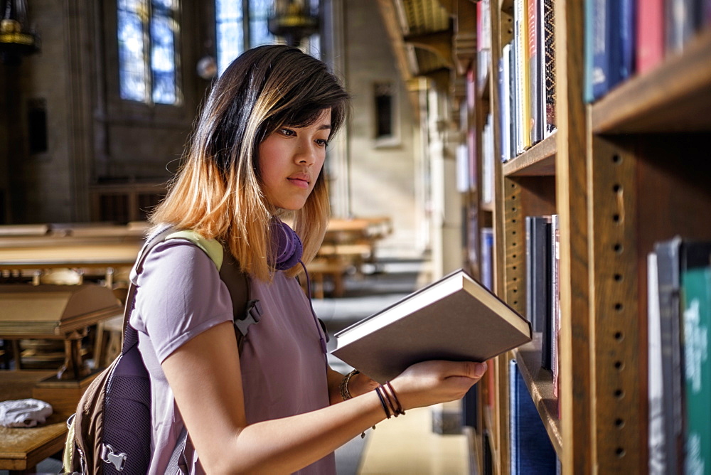 Chinese woman standing in library reading book