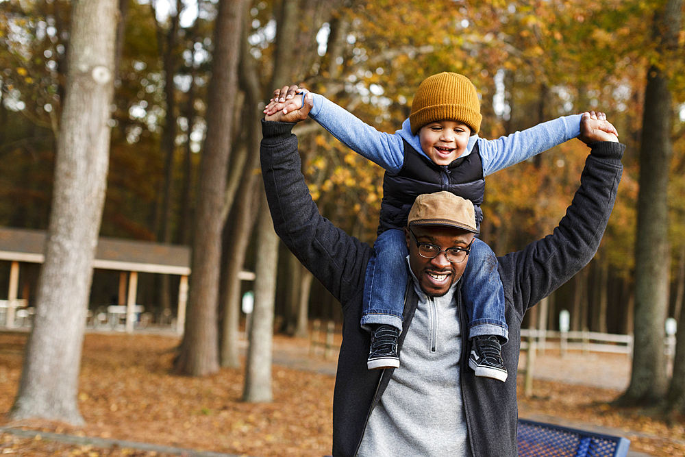 Father carrying son on shoulders in park