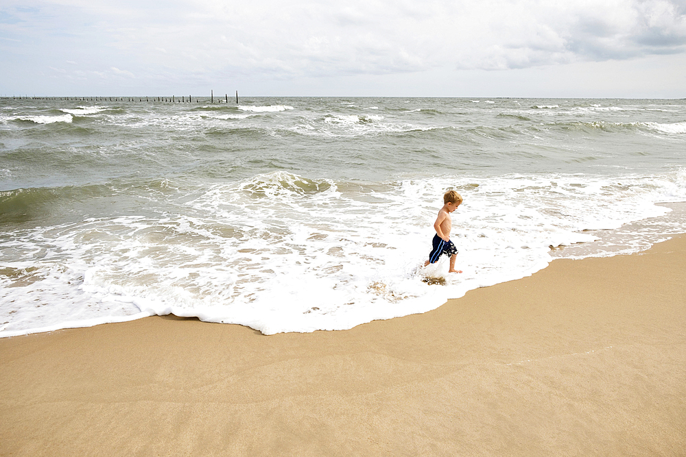 Caucasian boy running in waves at beach