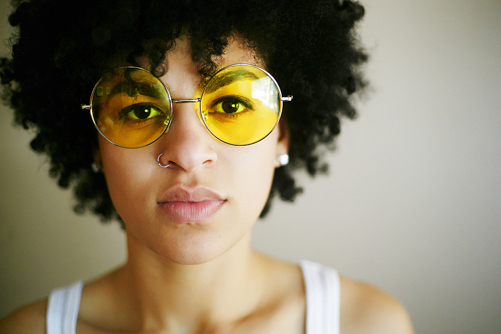 Portrait of serious Mixed Race woman wearing yellow sunglasses