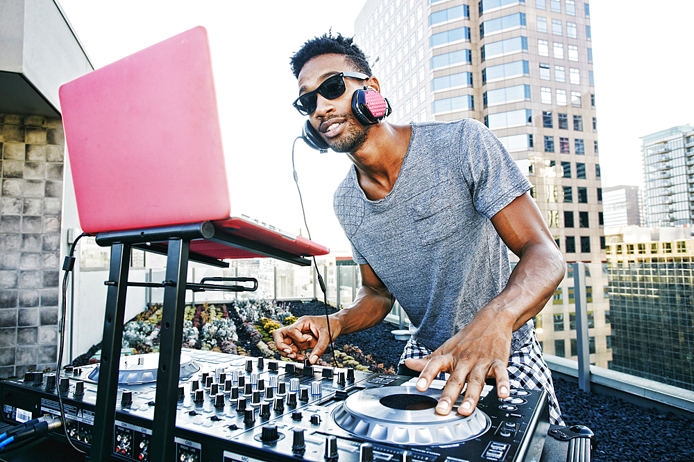 Smiling Black DJ on urban rooftop