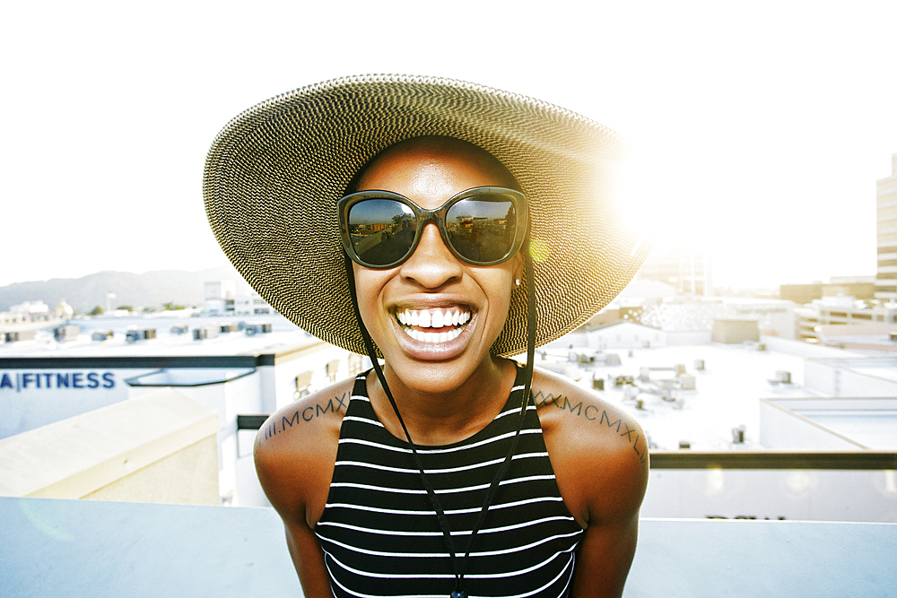 Black woman wearing sun hat and sunglasses on rooftop