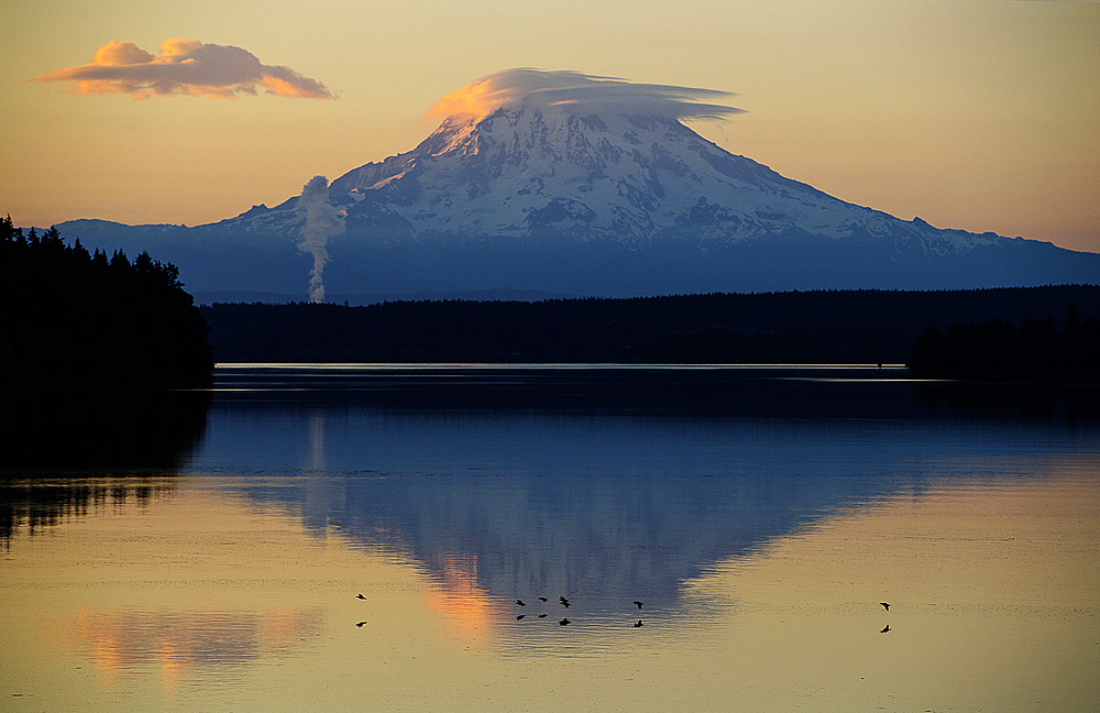 Reflection of clouds and mountain in river at sunset