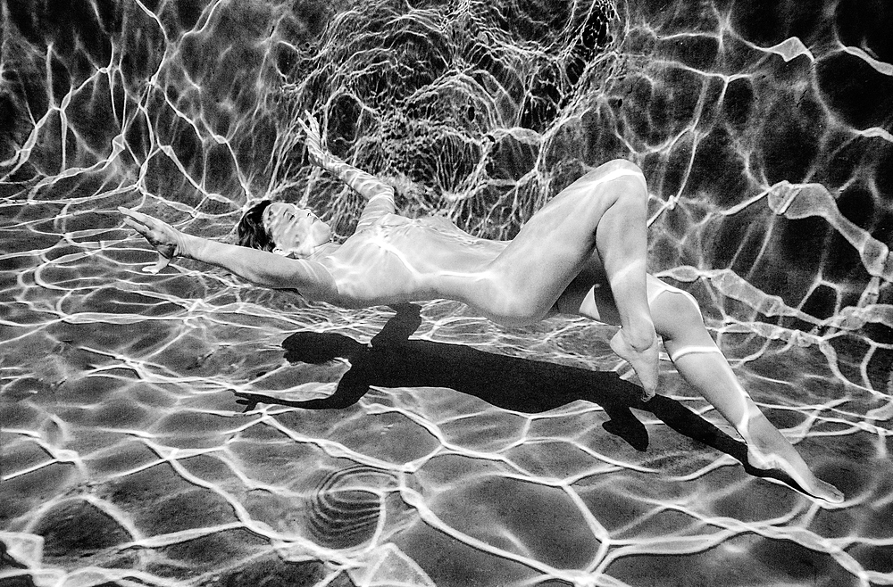 Naked Caucasian woman swimming underwater