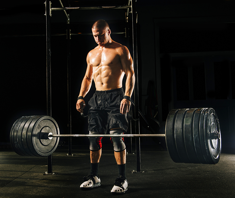 Man dropping heavy barbell in gymnasium