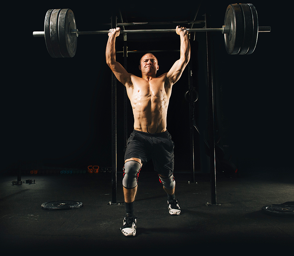 Man lifting heavy barbell in gymnasium