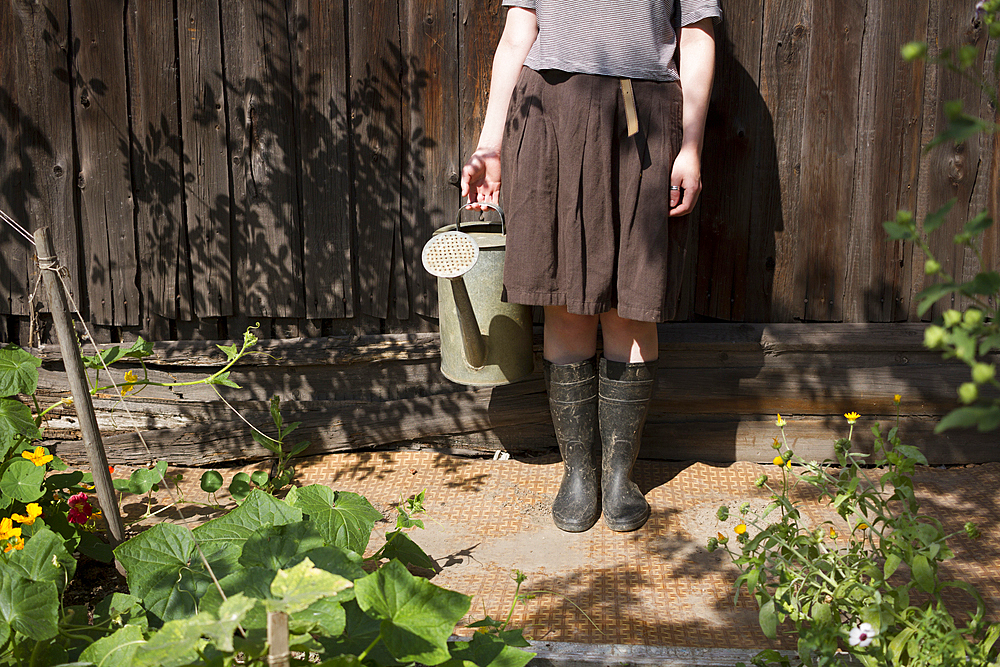 Caucasian woman holding watering can in garden