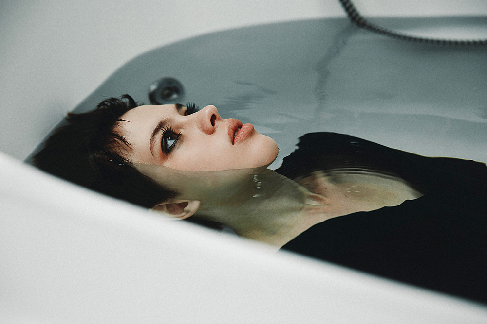 Caucasian woman wearing dress in bathtub