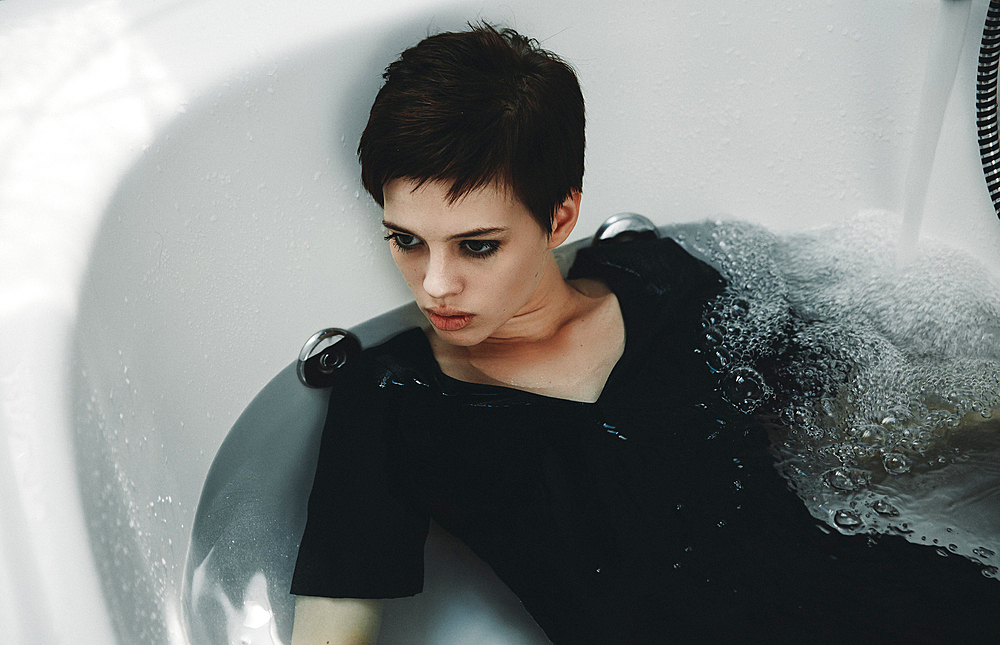 Caucasian woman wearing dress in bathtub