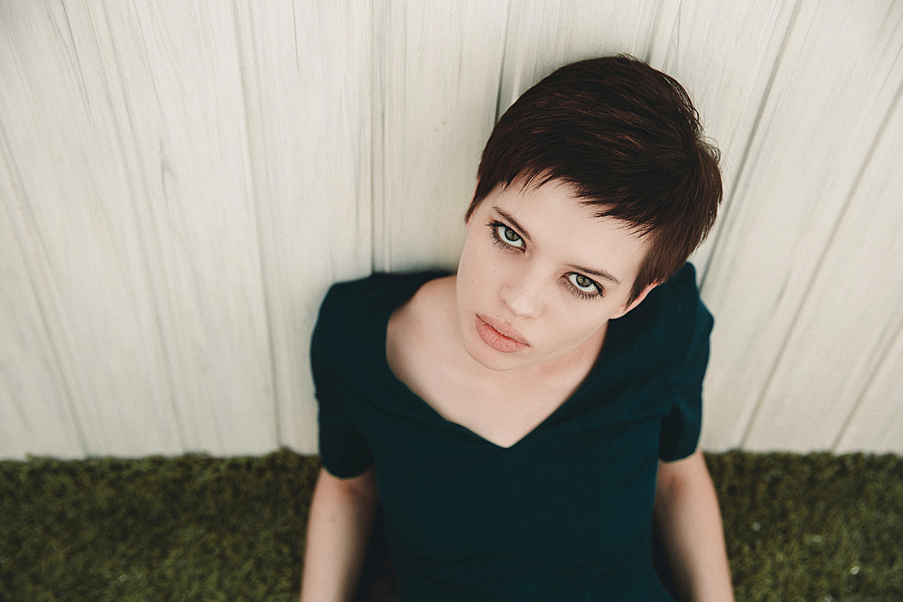 Portrait of serious Caucasian woman leaning on fence