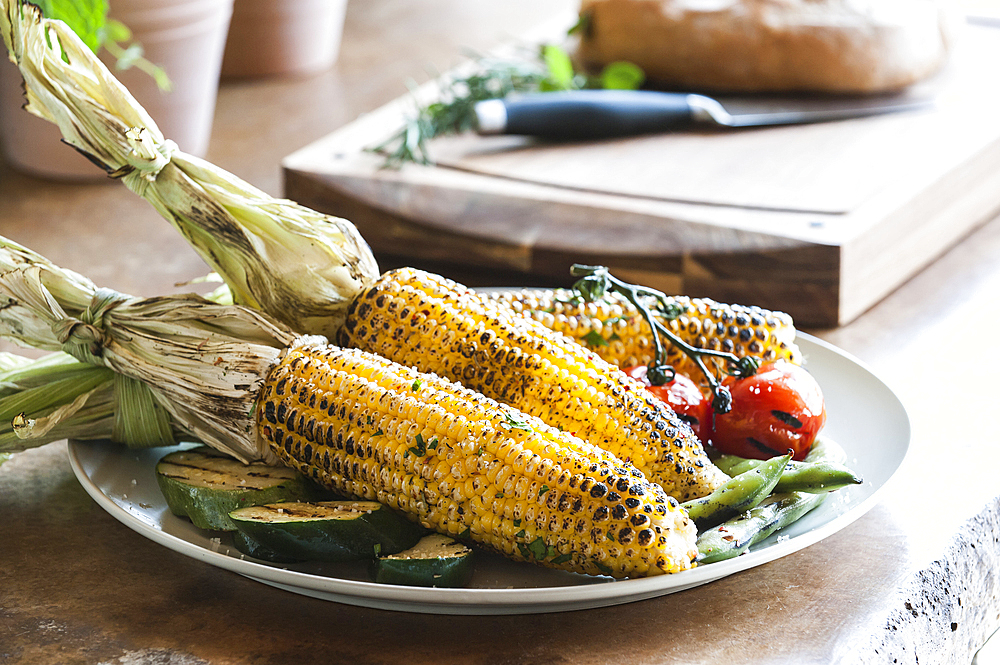 Plate of grilled corn, tomatoes and zucchini