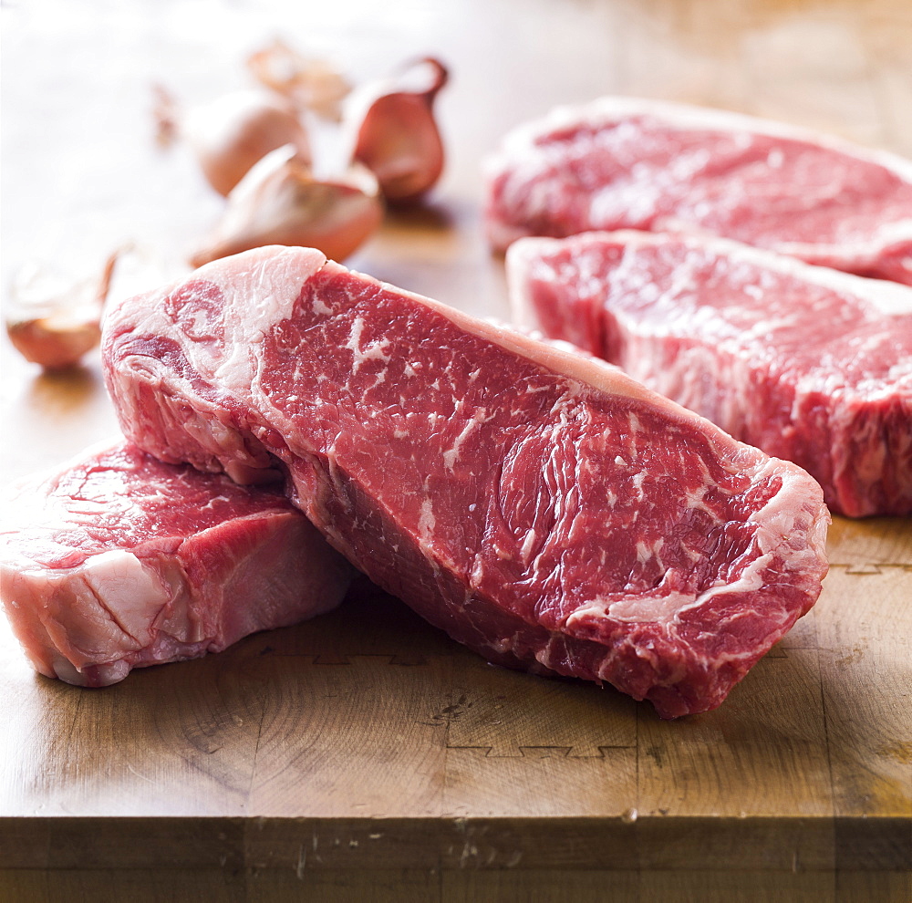 Raw steaks on wooden table