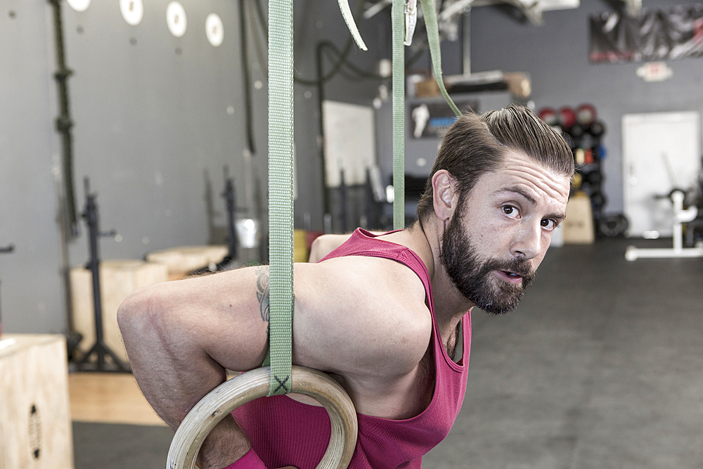 Mixed Race man working out with rings in gymnasium