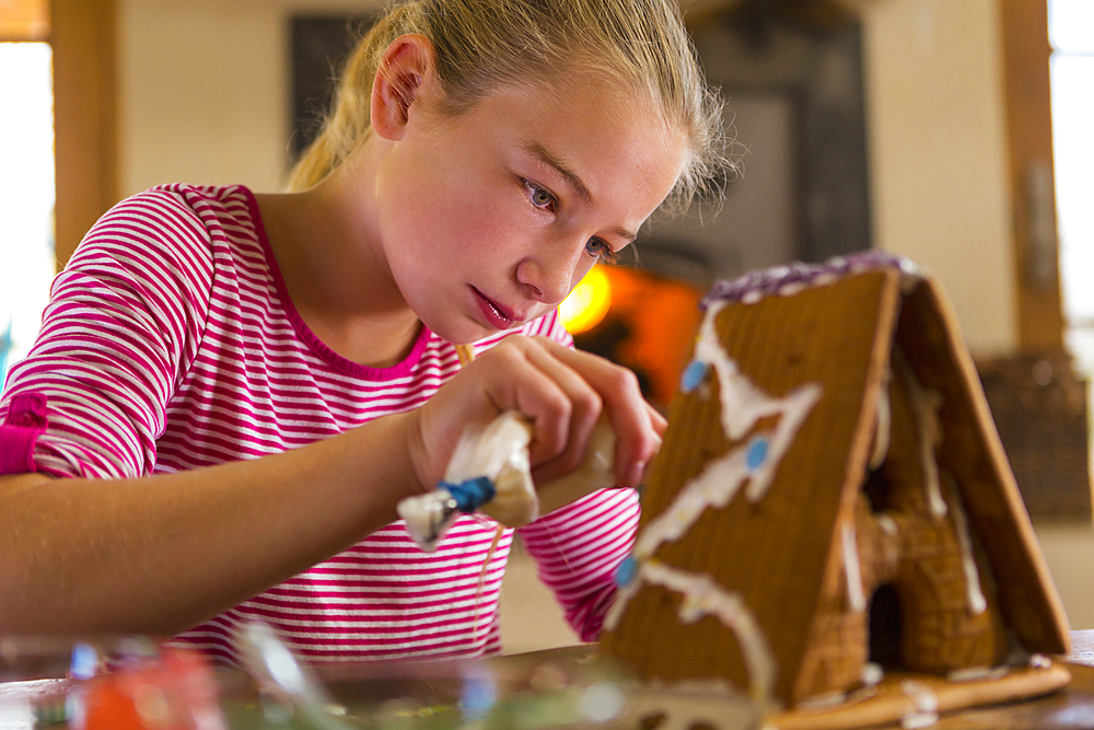 Caucasian girl spreading icing on gingerbread house