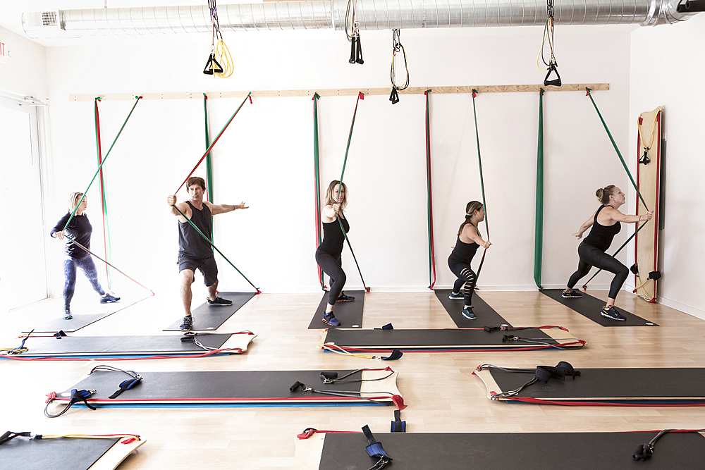 People pushing on resistance bands in gymnasium