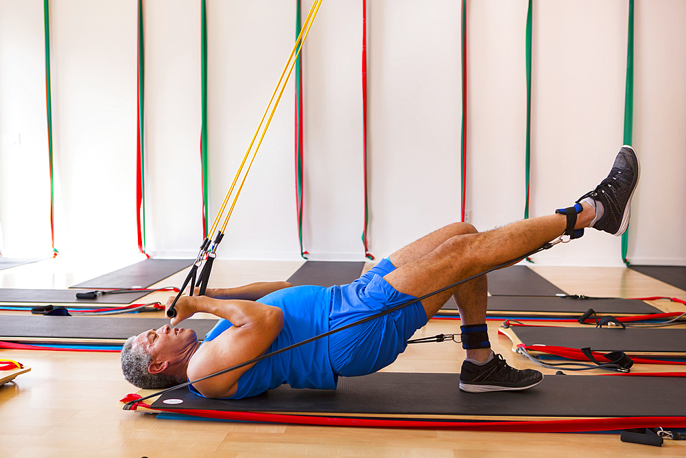 Mixed Race man using resistance bands in gymnasium