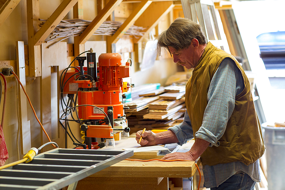 Caucasian carpenter writing on notepad in workshop