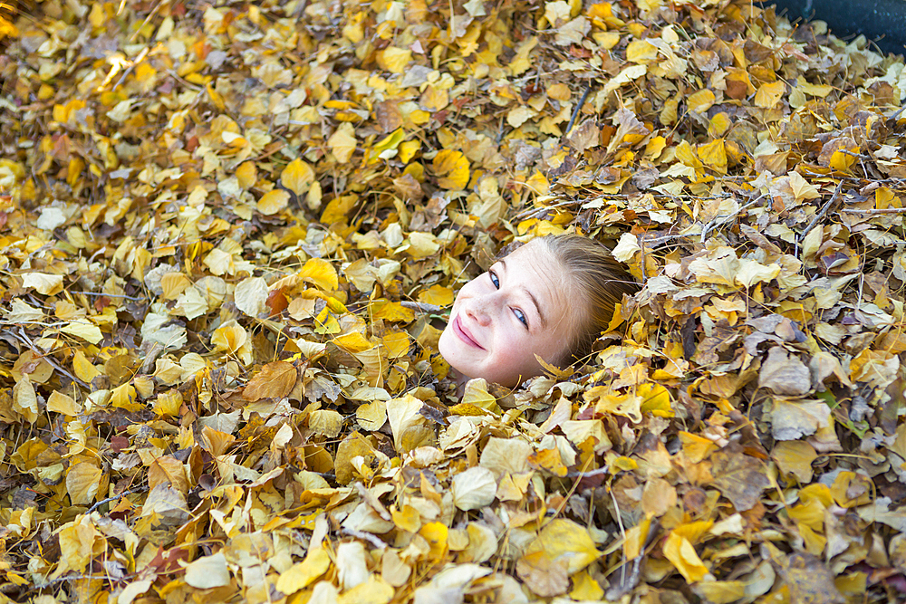 Face of Caucasian girl playing in autumn leaves