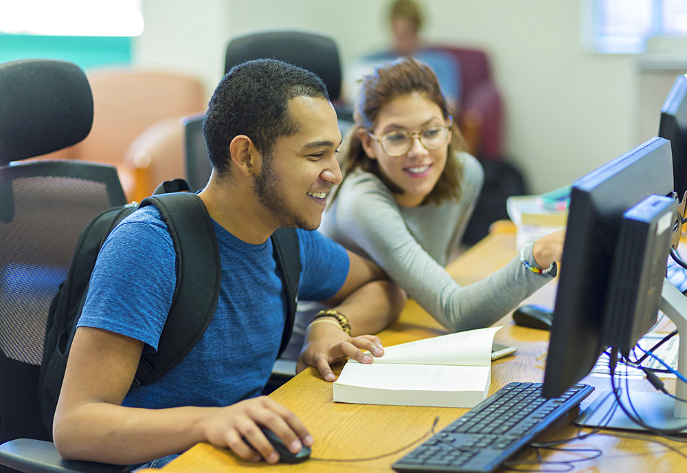 Mixed Race boy and girl using computer in library