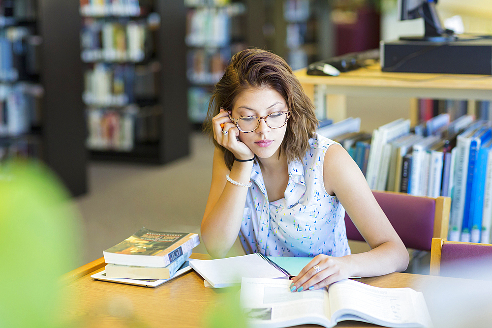 Mixed Race girl reading book in library