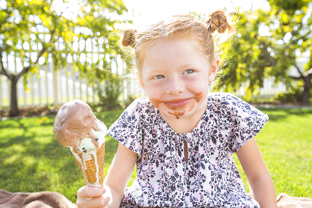 Caucasian girl with messy face eating ice cream cone