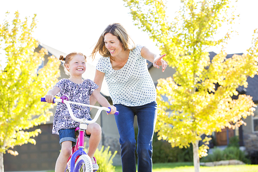 Caucasian mother teaching daughter to ride bicycle