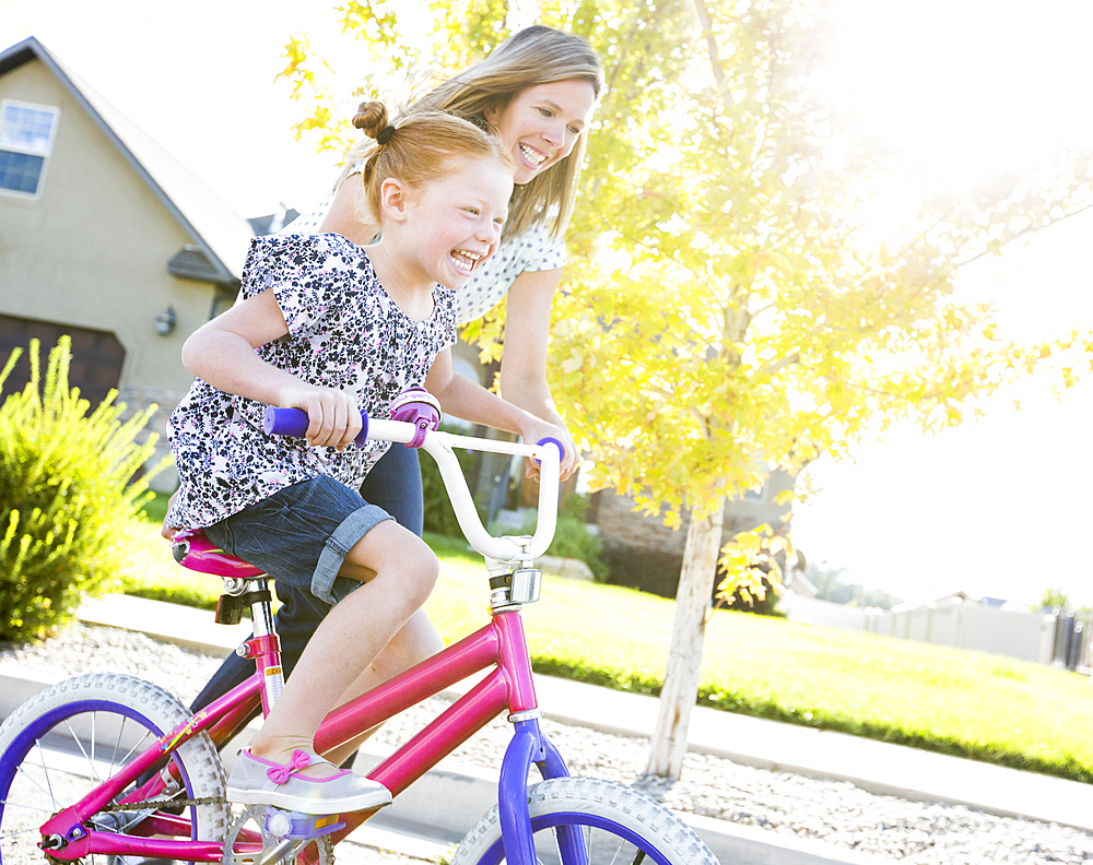 Caucasian mother teaching daughter to ride bicycle