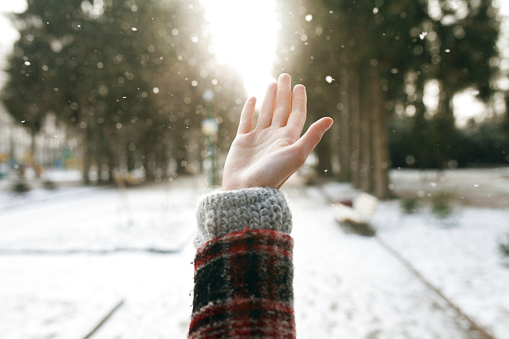 Hand of Caucasian woman catching falling snow