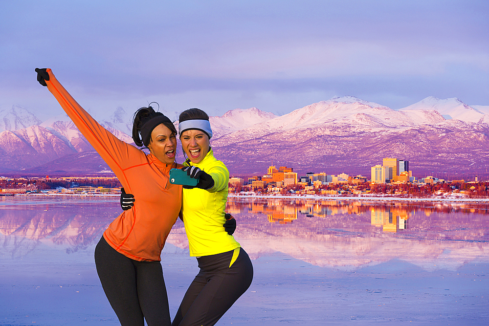 Women posing for cell phone selfie near mountain river