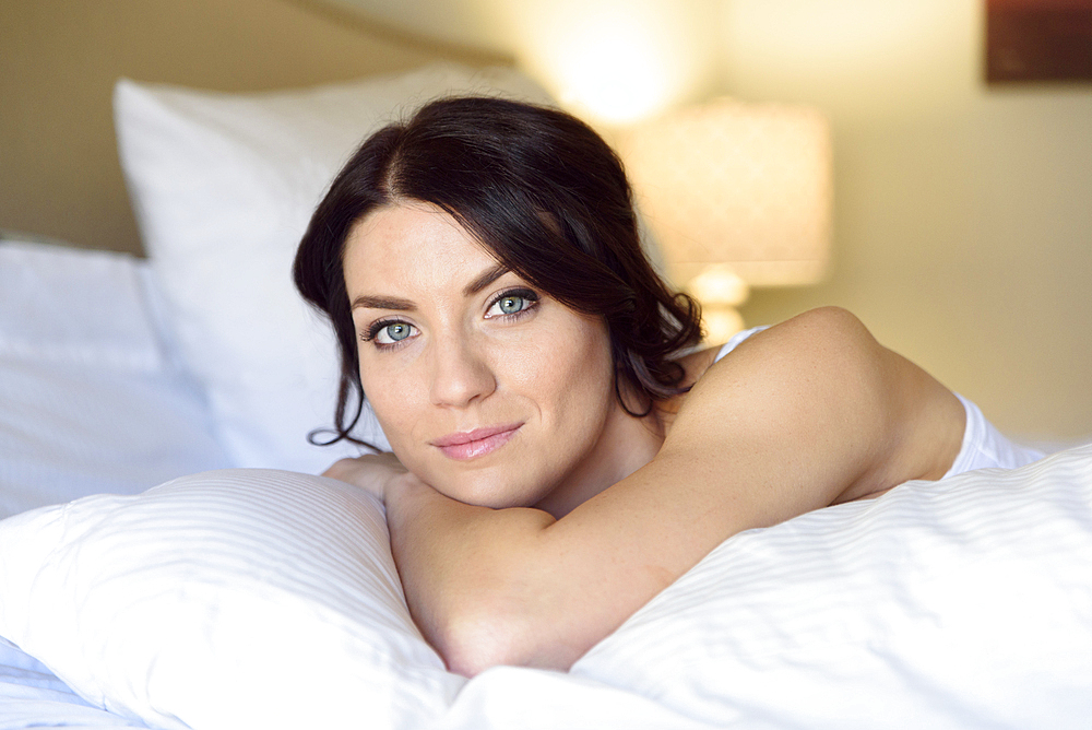 Smiling Caucasian woman laying on bed