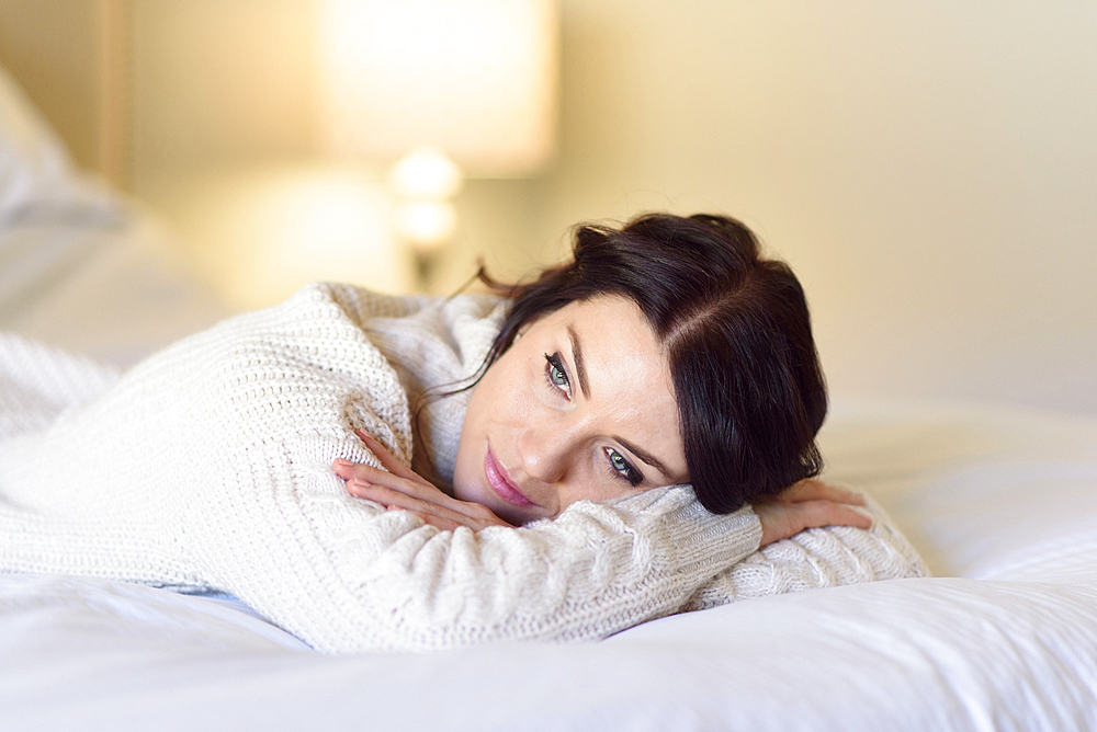 Caucasian woman daydreaming on bed